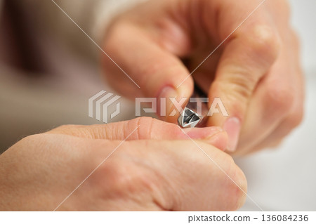Person removing excess skin from fingertips for neat and healthy nails Person removing excess skin from fingertips for neat and healthy nails 136084236
