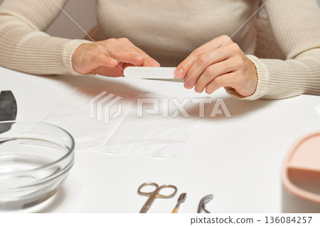 Woman's hands filing fingernails, performing self-care and beauty hygiene Woman's hands filing fingernails, performing self-care and beauty hygiene 136084257