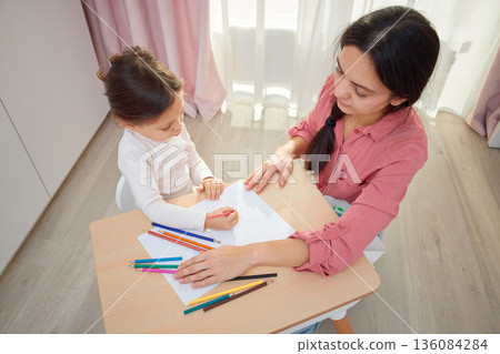 Mother and her daughter drawing with colored pencils, engaging in creative home learning, top view Mother and her daughter drawing with colored pencils, engaging in creative home learning, top view 136084284