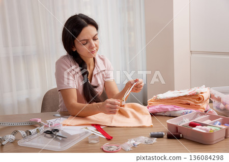 Woman sewing a zipper onto fabric, engaging in a creative hobby Woman sewing a zipper onto fabric, engaging in a creative hobby 136084298