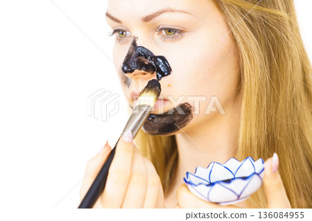 Girl being apply carbo mask to skin face Girl being apply carbo mask to skin face 136084955