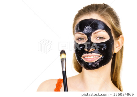 Woman applying black mud mask to face Woman applying black mud mask to face 136084969