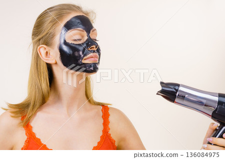 Girl drying peel-off black mask on face 136084975