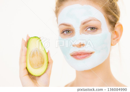 Girl facial mud mask holds avocado fruit Girl facial mud mask holds avocado fruit 136084990