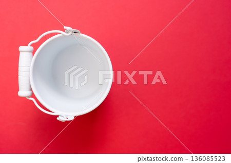 White bucket of miscellaneous goods on a red background 136085523