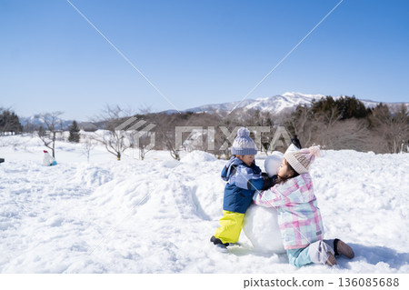 Children making snowmen and playing in the snow Children making snowmen and playing in the snow 136085688