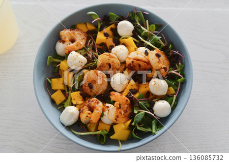 Salad with mango, mozzarella, shrimps and mixed microgreens in blue bowl on white oak table Salad with mango, mozzarella, shrimps and mixed microgreens in blue bowl on white oak table 136085732