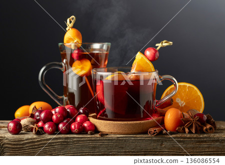 Winter drinks with spices, cranberries, and citrus fruits on a dark background. Winter drinks with spices, cranberries, and citrus fruits on a dark background. 136086554
