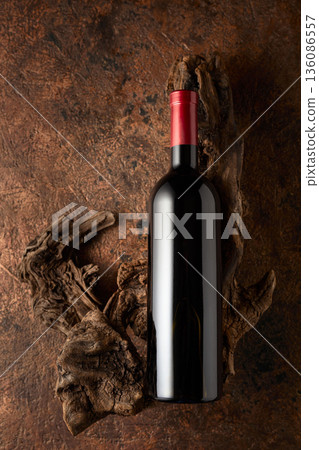 Bottle of red wine and old weathered snags on a brown vintage background. 136086557