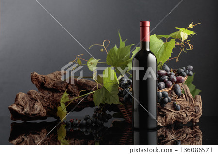 Bottle of red wine with blue grapes and vine branches. Bottle of red wine with blue grapes and vine branches. 136086571