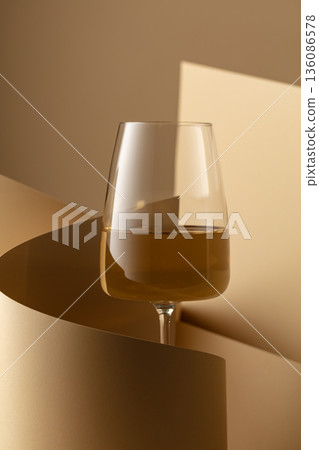Glass of white wine on a beige background. Glass of white wine on a beige background. 136086578