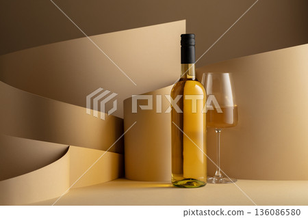 Bottle and glass of white wine on a beige background. Bottle and glass of white wine on a beige background. 136086580