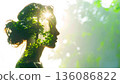 A silhouette of a woman's profile reflecting the sunlight filtering through the trees (image of coexistence with nature and forest conservation) 136086822