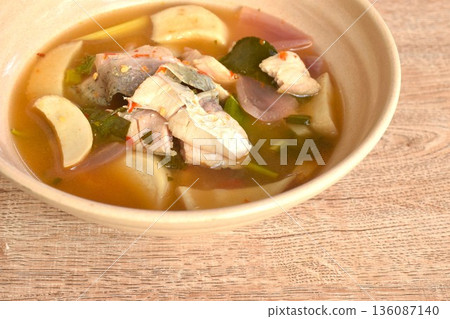 boiled bass fish meat and mushroom in clear tom yum Thai herb soup on plate boiled bass fish meat and mushroom in clear tom yum Thai herb soup on plate 136087140
