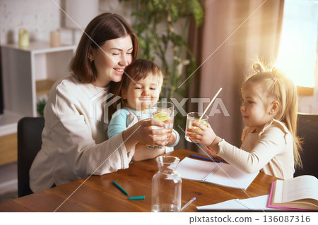 Family drinking water during children drawing activity at home table. Family drinking water during children drawing activity at home table. 136087316