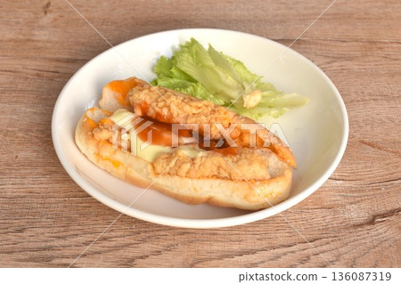 hot dog stuffed crispy fried chicken with lettuce dressing ketchup and mayonnaise on dish 136087319