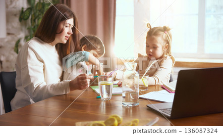 Family drawing at table with glass of water nearby. Family drawing at table with glass of water nearby. 136087324