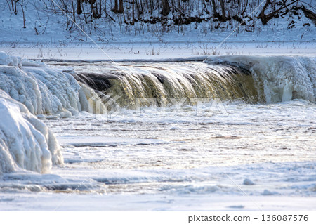 Water flowing over a frozen river in winter with ice forming along the bank Water flowing over a frozen river in winter with ice forming along the bank 136087576