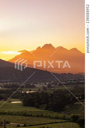 Sunset over mountain range and vineyard landscape in Cape Winelands, South Africa, showcasing wine region and scenic beauty for travel Sunset over mountain range and vineyard landscape in Cape Winelands, South Africa, showcasing wine region and scenic beauty for travel 136088952