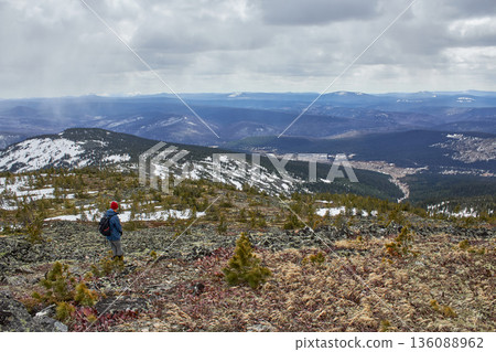 Man hiking with backpack on mountain slope under gray sky. Outdoor adventure exploring wilderness. Nature exploration for travel blog. Man hiking with backpack on mountain slope under gray sky. Outdoor adventure exploring wilderness. Nature exploration for travel blog. 136088962