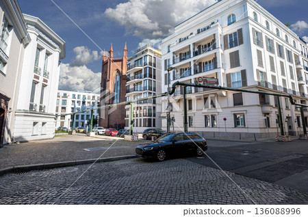 Berlin, Germany, August 11, 2023. Urban street scene, showing the historic Friedrichswerder Church surrounded by contemporary buildings and prominent green pipes of the city's water supply. Berlin, Germany, August 11, 2023. Urban street scene, showing the historic Friedrichswerder Church surrounded by contemporary buildings and prominent green pipes of the city's water supply. 136088996