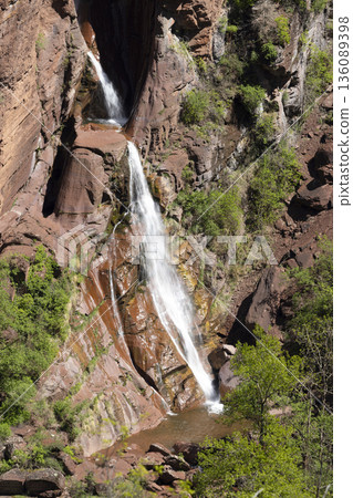 Waterfall cascading down red rock formations in Guillaumes 136089398
