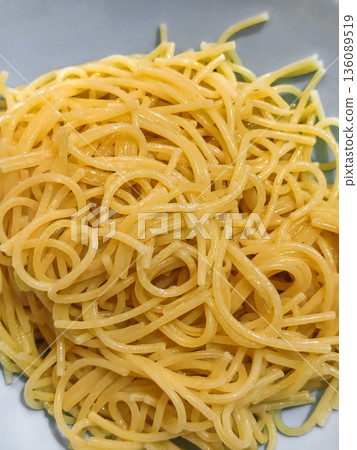 A bowl contains long, thin strands of spaghetti. The pasta is freshly cooked and awaiting sauce or toppings for a meal A bowl contains long, thin strands of spaghetti. The pasta is freshly cooked and awaiting sauce or toppings for a meal 136089519