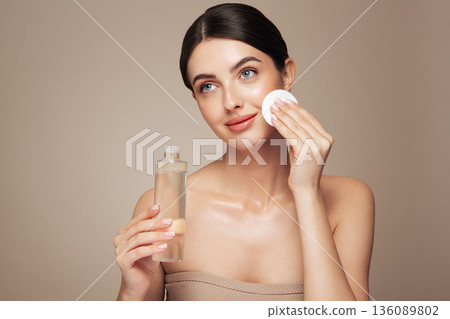 Young woman cleansing face with cosmetic milk Young woman cleansing face with cosmetic milk 136089802