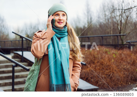 Woman in a coat talking on the phone Woman in a coat talking on the phone 136089803
