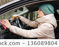 An adult woman is cleaning her car 136089804