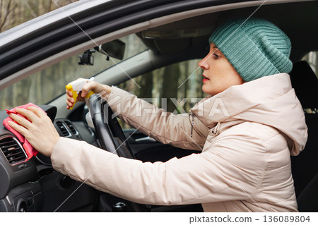 An adult woman is cleaning her car An adult woman is cleaning her car 136089804