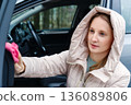 A young woman on the street is cleaning in her car 136089806