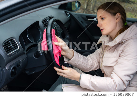 An adult woman is cleaning her car An adult woman is cleaning her car 136089807