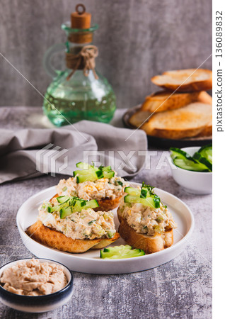 Delicious sandwiches with cod liver salad, egg and cucumber on a plate on the table vertical view Delicious sandwiches with cod liver salad, egg and cucumber on a plate on the table vertical view 136089832
