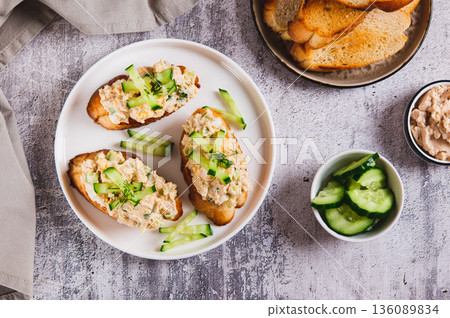 Delicious sandwiches with cod liver salad, egg and cucumber on a plate on the table top view 136089834