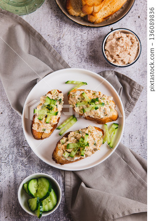 Cod liver, egg, cucumber salad on toast on a plate on the table top and vertical view Cod liver, egg, cucumber salad on toast on a plate on the table top and vertical view 136089836