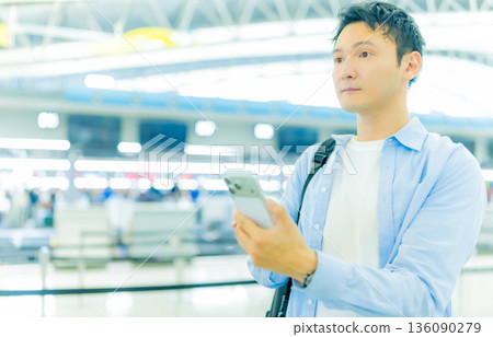 一名男子在機場使用智慧型手機。照片由關西國際機場(KIX)提供。 一名男子在機場使用智慧型手機。照片由關西國際機場(KIX)提供。 136090279