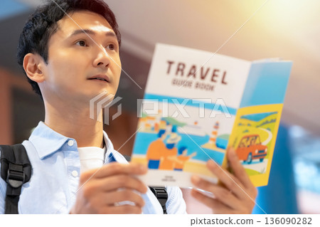 一名男子正在閱讀旅遊指南。照片由關西國際機場(KIX)提供。 一名男子正在閱讀旅遊指南。照片由關西國際機場(KIX)提供。 136090282