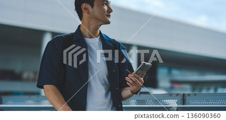 A man operating his mobile phone at the airport. Photo courtesy of Kansai International Airport (KIX) 136090360