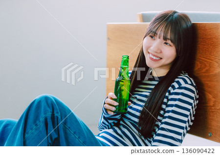 Young woman drinking beer in the living room 136090422
