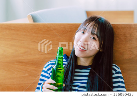 Young woman drinking beer in the living room Young woman drinking beer in the living room 136090423