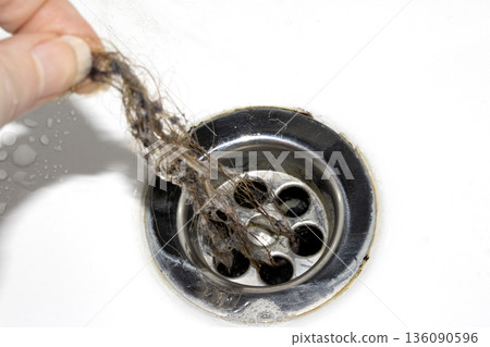 Unblocking brown hair from sink hole drain close up unhygenic gross job 136090596