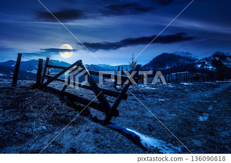 rural landscape of carpathian mountains in early spring under dark sky at night. snow covered hill with barbed wire fence in full moon light. inner strength to overcome fear, loneliness in darkness rural landscape of carpathian mountains in early spring under dark sky at night. snow covered hill with barbed wire fence in full moon light. inner strength to overcome fear, loneliness in darkness 136090818