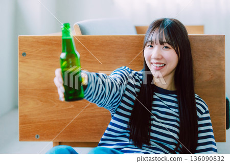 Young woman drinking beer in the living room 136090832