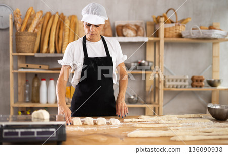 Elderly woman baker making pieces of dough Elderly woman baker making pieces of dough 136090938