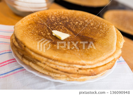 freshly baked hot cereal pancakes on plate and pans during cooking 136090948