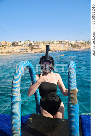 A woman overcomes her fear as she puts on a snorkel mask for the first time and dives into the water A woman overcomes her fear as she puts on a snorkel mask for the first time and dives into the water 136091240