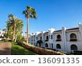 A white hotel building in an Arabian resort with green planted grounds 136091335