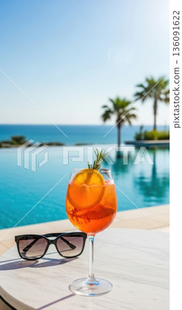 Vibrant Orange Spritz Cocktail on Poolside Table Under Clear Sky Vibrant Orange Spritz Cocktail on Poolside Table Under Clear Sky 136091622