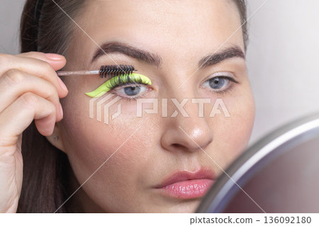 Caucasian woman twists her eyelashes on her own. A woman laminates eyelashes, comb lashes on a silicone roller. close up Caucasian woman twists her eyelashes on her own. A woman laminates eyelashes, comb lashes on a silicone roller. close up 136092180